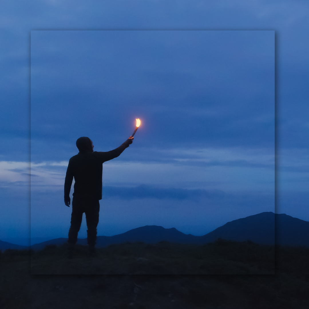 Man holding a candle to the dusk sky